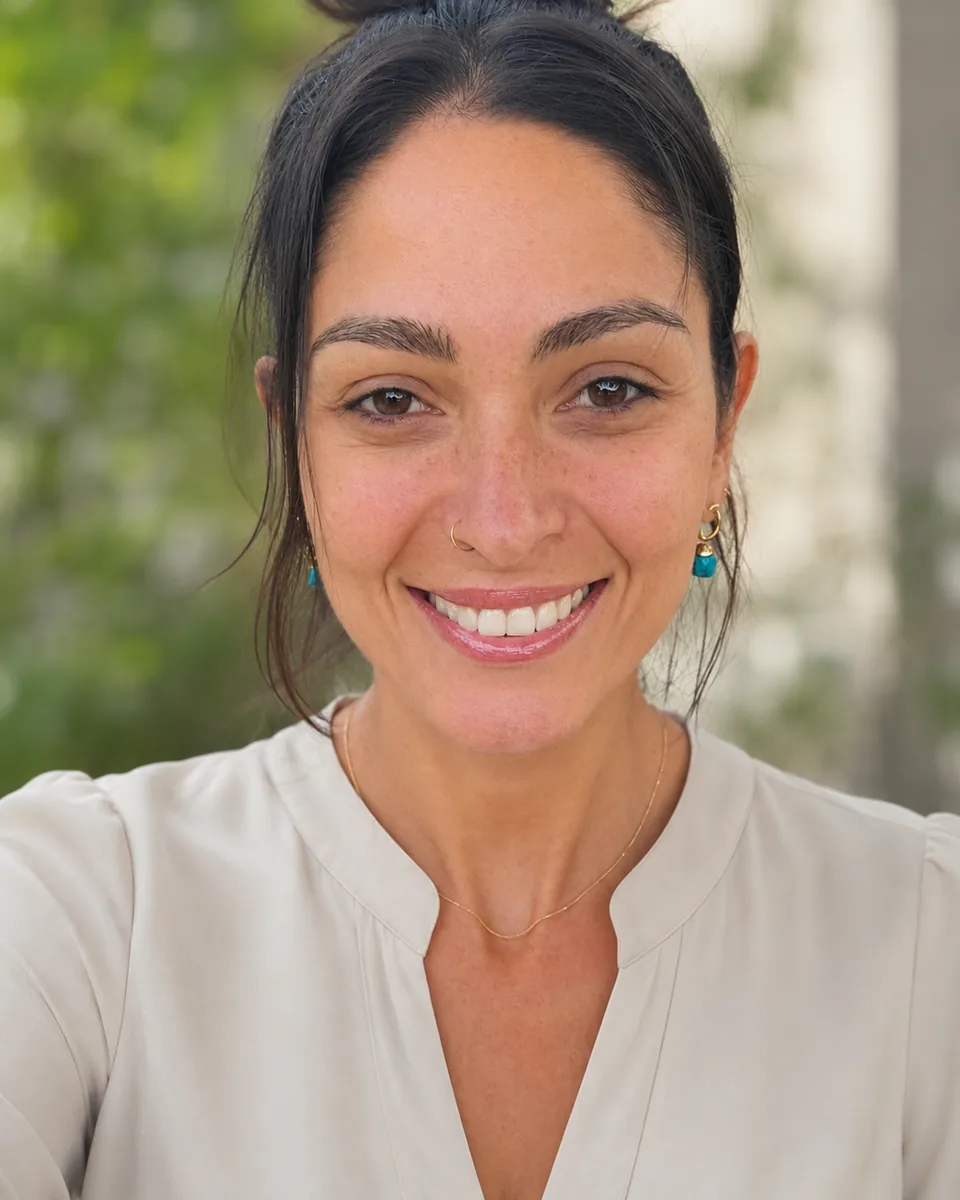 Juliana Sanches sorrindo, com cabelo preso e blusa clara